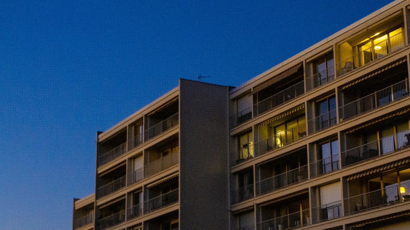 Bloque de viviendas al anochecer con las ventanas iluminadas